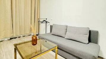 Ein Wohnzimmer mit einer Couch, einem Glastisch und einer Lampe.