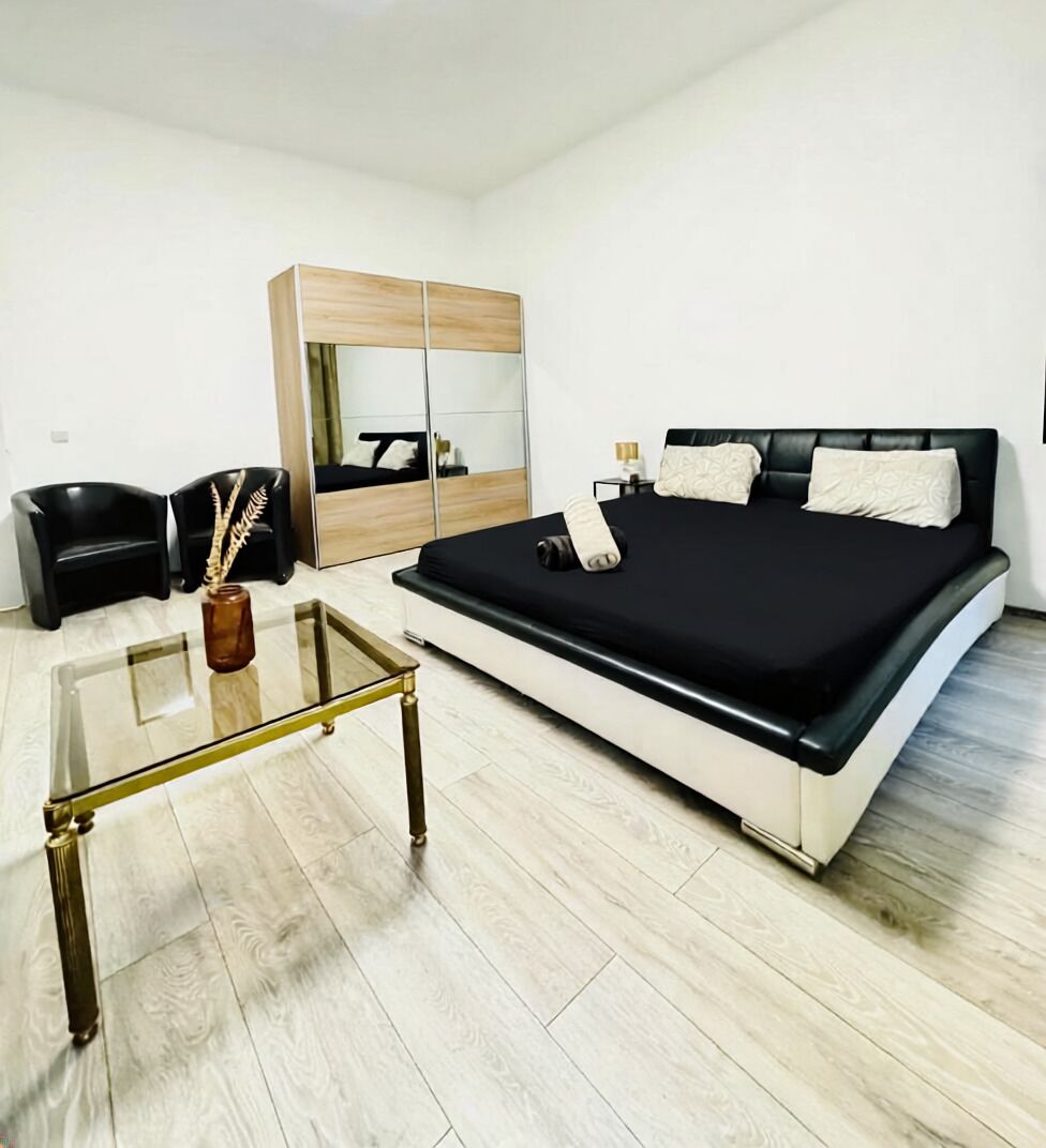 Ein Schlafzimmer mit Bett, Nachttisch, Spiegel, Kleiderschrank und Stuhl.