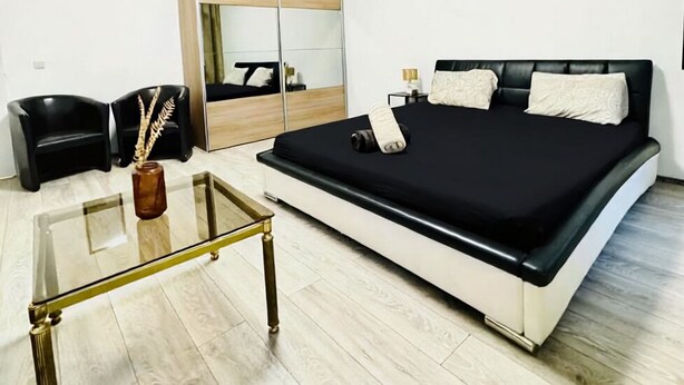 A bedroom with a bed, a bedside table, a mirror, a wardrobe, and a chair. - Comfy Room in a Shared Apt, Near FAC Platz (Vienna)