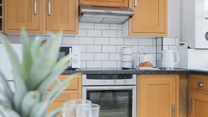 Une cuisine avec des meubles de rangement en bois, un four à micro-ondes, un grille-pain et une machine à café.