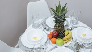 Une table dressée pour un repas, avec des assiettes, des couverts, des verres et une composition de fruits.