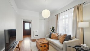 Een moderne woonkamer met een flatscreen televisie, een houten salontafel en een bank met kussens.