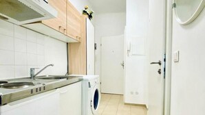 A kitchen with a double sink, a washing machine, and a door leading to another room. - 1BR Apt for 5P, 10-Min Transport to Stadthalle (Vienna)
