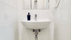A bathroom with a white sink, a mirror above it, and a showerhead on the wall. - 1BR Apt for 5P, 10-Min Transport to Stadthalle (Vienna)