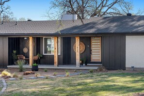 A modern house with a dark exterior, a wooden porch, and a number '425' on the door. - Near AT&T | Hot Tub • Pickleball • Sleeps 14 (Arlington)