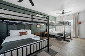 A bunk bed room with a ceiling fan, a small table, and a window with curtains. - Near AT&T | Hot Tub • Pickleball • Sleeps 14 (Arlington)