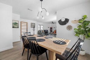 A modern dining area with a wooden table, black chairs, and a ceiling fan. - Near AT&T | Hot Tub • Pickleball • Sleeps 14 (Arlington)