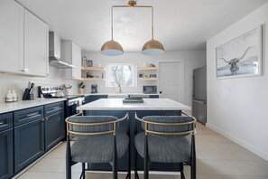 A modern kitchen with dark cabinets, a central island, and two bar stools.