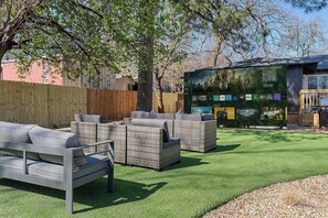 A backyard with outdoor furniture, a wooden fence, and a large screen displaying movie posters.