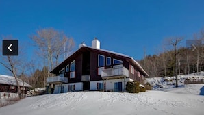 A two-story house with a balcony, surrounded by snow and trees. - Amazing  2-bedroom condo above Story Land with AC, WiFi in beautiful Bartlett (Bartlett)