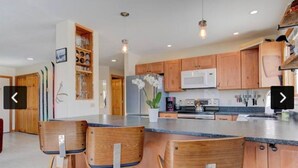A modern kitchen with wooden cabinets, a central island with bar stools, and a microwave. - Amazing  2-bedroom condo above Story Land with AC, WiFi in beautiful Bartlett (Bartlett)