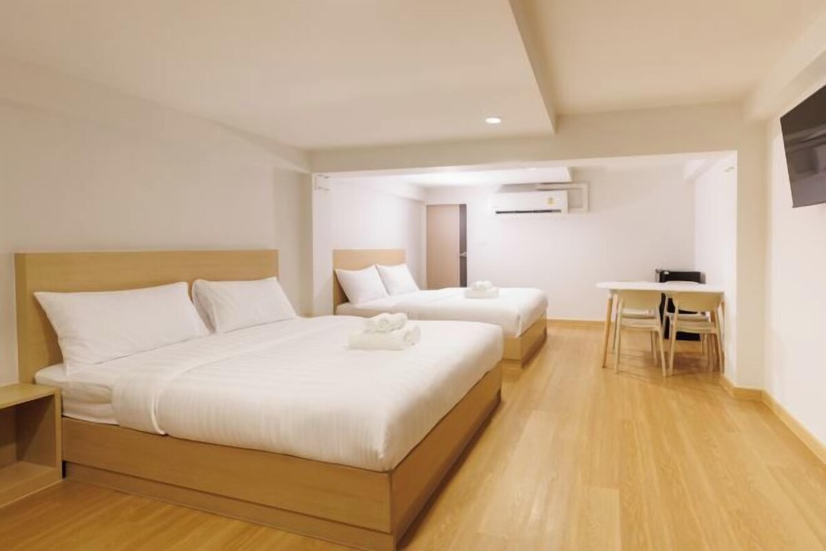 A hotel room with two beds, a desk, and a chair.