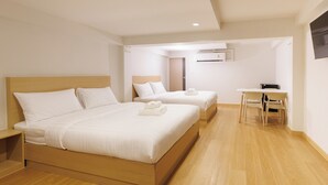 A hotel room with two beds, a desk, and a chair.
