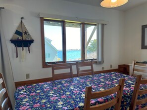 A room with a large window, a bed with a floral bedspread, and a wooden chair. - Enjoy Stunning Ocean Views & Coastal Access at Sea Mist Overlook! (Harpswell)