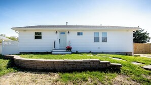 A single-story white house with a front porch, a small front yard, and a brick retaining wall. - Cozy Dog-Friendly Cape May Escape- Short Walk to Beach (Lower Township)