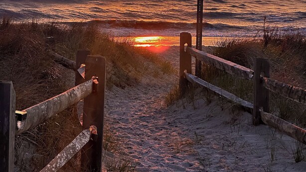 A sunset over the ocean with a wooden pathway leading to the water. - Cozy Dog-Friendly Cape May Escape- Short Walk to Beach (Lower Township)