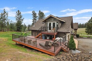 A two-story house with a balcony, a deck, and a covered porch. - High-end studio on five acre estate with over 100 five star reviews! (Newman lake)