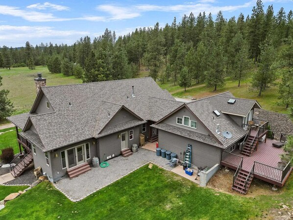 A large, two-story house with a spacious deck and a stone chimney. - High-end studio on five acre estate with over 100 five star reviews! (Newman lake)