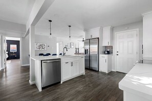 A modern kitchen with white cabinetry, stainless steel appliances, and a wooden floor. - 1.4 Mi to AT&T | Mini Golf + Hoops | Sleeps 12 (Arlington)