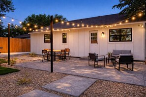 A house with a patio, outdoor seating, and string lights. - Sleeps 12 | Pickleball + Mini Golf + Pool Table (Arlington)