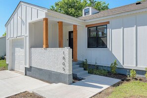 A residential house with a garage, a covered porch with wooden columns, and a stone wall with the number 1805. - 1.4 Mi to AT&T | Mini Golf + Hoops | Sleeps 12 (Arlington)
