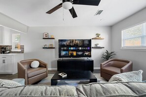 A modern living room with a flat-screen TV, two leather sofas, a coffee table, and a ceiling fan. - 1.4 Mi to AT&T | Mini Golf + Hoops | Sleeps 12 (Arlington)