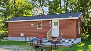 A small, single-story cabin with a front porch, a grill, and outdoor seating. - Relax in the Fox Den | Private 2BR Cabin Close to Beach & Activities (Isle)