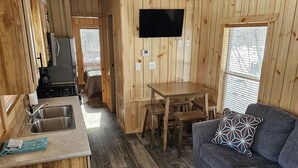 A wooden cabin interior with a kitchen, dining area, and a sofa. - Relax in the Fox Den | Private 2BR Cabin Close to Beach & Activities (Isle)