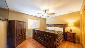 Une chambre à coucher avec un lit en bois, un ventilateur de plafond, une table de chevet avec une lampe et une armoire.