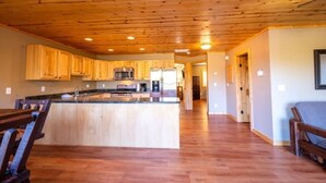 Une cuisine spacieuse dotée de meubles en bois et d’un îlot central, qui est reliée à un coin repas agrémenté d’une banquette.