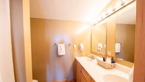 Un baño con pared color beige, un lavamanos blanco y un espejo grande.