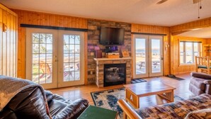 Un salón acogedor con chimenea, televisor y un amplio ventanal con vistas panorámicas.