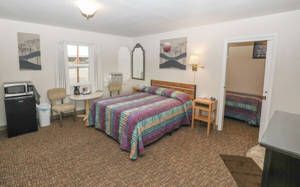 A hotel room with a bed, a desk, a chair, a microwave, and a trash bin. - Condon Motel (Condon)