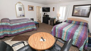 A hotel room with two beds, a TV, a wooden table, and a desk with a lamp. - Condon Motel (Condon)