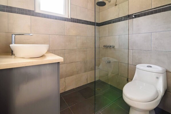 A bathroom with a white sink, a glass shower enclosure, and a toilet.