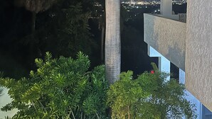 Een nachtzicht van een gebouw met een balkon dat uitkijkt op een stadsgezicht.