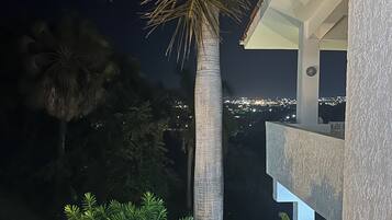 Ein Nachtblick auf ein Gebäude mit einem Balkon, der auf einen Stadtblick blickt.