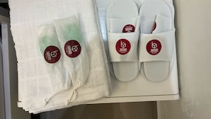 Eine Schachtel mit einem weißen Handtuch, weißen Hausschuhen und einer weißen Badmatte.