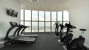 Une salle de sport équipée de tapis de course, de vélos d’appartement et d’un téléviseur fixé au mur.