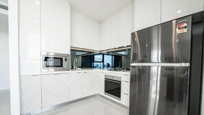 Une cuisine moderne dotée d’appareils électroménagers en acier inoxydable, de meubles blancs et d’un dosseret en marbre à motifs en chevrons.