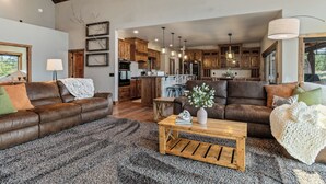 A spacious living room with a brown leather sofa, a wooden coffee table, and a gray carpet.