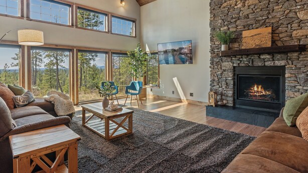 A spacious living room with a stone fireplace, large windows, and a cozy seating area.