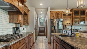 A kitchen with wooden cabinets, granite countertops, and stainless steel appliances.