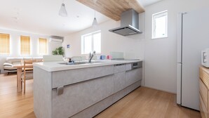 A modern kitchen with a large island, wooden ceiling, and a built-in dishwasher. - THE MAISON CHOUCHOU  (Sapporo)