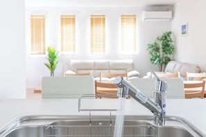 Eine moderne Küche mit einer Edelstahlspüle, einem Wasserhahn und einem Fenster mit Jalousien.