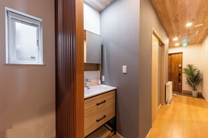 Ein modernes Badezimmer mit einem Holzlager, einem weißen Waschbecken und einem Spiegel.