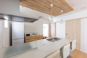 A modern kitchen with a large island, stainless steel appliances, and wooden ceiling beams. - THE MAISON CHOUCHOU  (Sapporo)