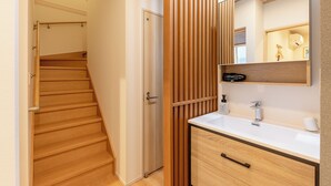 A modern bathroom with a wooden vanity, a sink, and a mirror. - THE MAISON CHOUCHOU  (Sapporo)