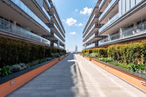 A modern building with multiple balconies, a central walkway, and a clear sky.