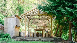 A wooden gazebo with a table and chairs, surrounded by a grassy area and trees. - Wayside Loft by Interhome (Drumnadrochit)